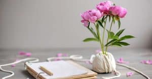 notepad and pencil with simple pink flower arrangement to signify easy self care ideas.