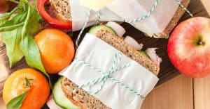 wrapped sandwiches tied with string with apple and oranges by the side to signify lunch ideas for husband.